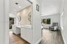 Double vanity featuring white cabinetry, square vessel sinks, and stone-tiled backsplash with circular wall-mounted mirrors and wood-finish flooring