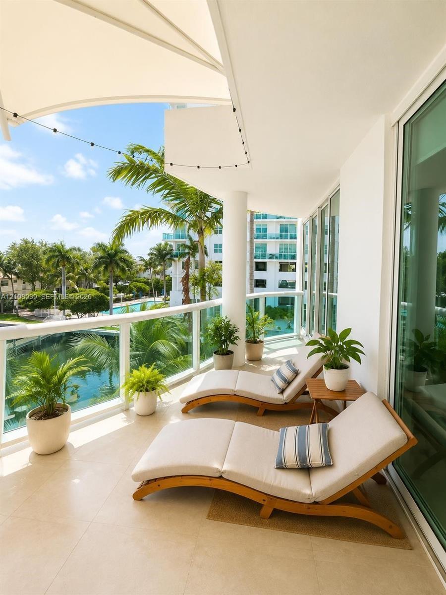Covered private balcony featuring tile flooring, glass panel railing, and a retractable tension canopy