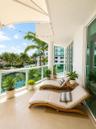 Covered private balcony featuring tile flooring, glass panel railing, and a retractable tension canopy