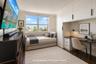 Room featuring wood-finish flooring, extensive built-in white cabinetry, integrated desk workspace with drawer storage, and a large window