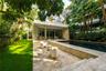 Outdoor terrace featuring natural stone paving, rectangular swimming pool, manicured lawn, and mature palm trees