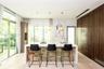 Kitchen featuring a central island with natural stone base and light-toned countertop, full-height dark wood-finish cabinetry, built-in cooktop, under