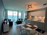 Open-concept interior featuring floor-to-ceiling glass doors, built-in cabinetry with matte finish, tile flooring, integrated kitchen appliances, and 