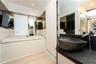 Recessed lighting, deep-basin vessel sink with a contemporary chrome faucet, matte black countertop, mirrored wall accents, and an integrated soaking 