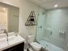 Bathroom featuring a vanity with a white countertop and undermount sink, large frameless mirror, and a walk-in shower enclosed by a glass door with li