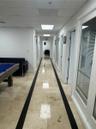 Hallway featuring polished stone tile flooring with decorative dark inlay, recessed lighting, and multiple doors with glass-panel inserts