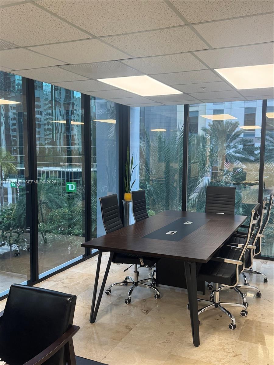 Floor-to-ceiling glass wall panels, stone tile flooring, and a suspended drop ceiling with recessed lighting
