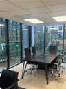 Floor-to-ceiling glass wall panels, stone tile flooring, and a suspended drop ceiling with recessed lighting