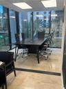 Floor-to-ceiling glass walls, polished stone flooring, recessed ceiling lighting, and integrated dark-finish built-in conference table