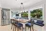 Dining area featuring large-format tile flooring, built-in window seating with integrated storage, stainless steel refrigerator with overhead wine rac