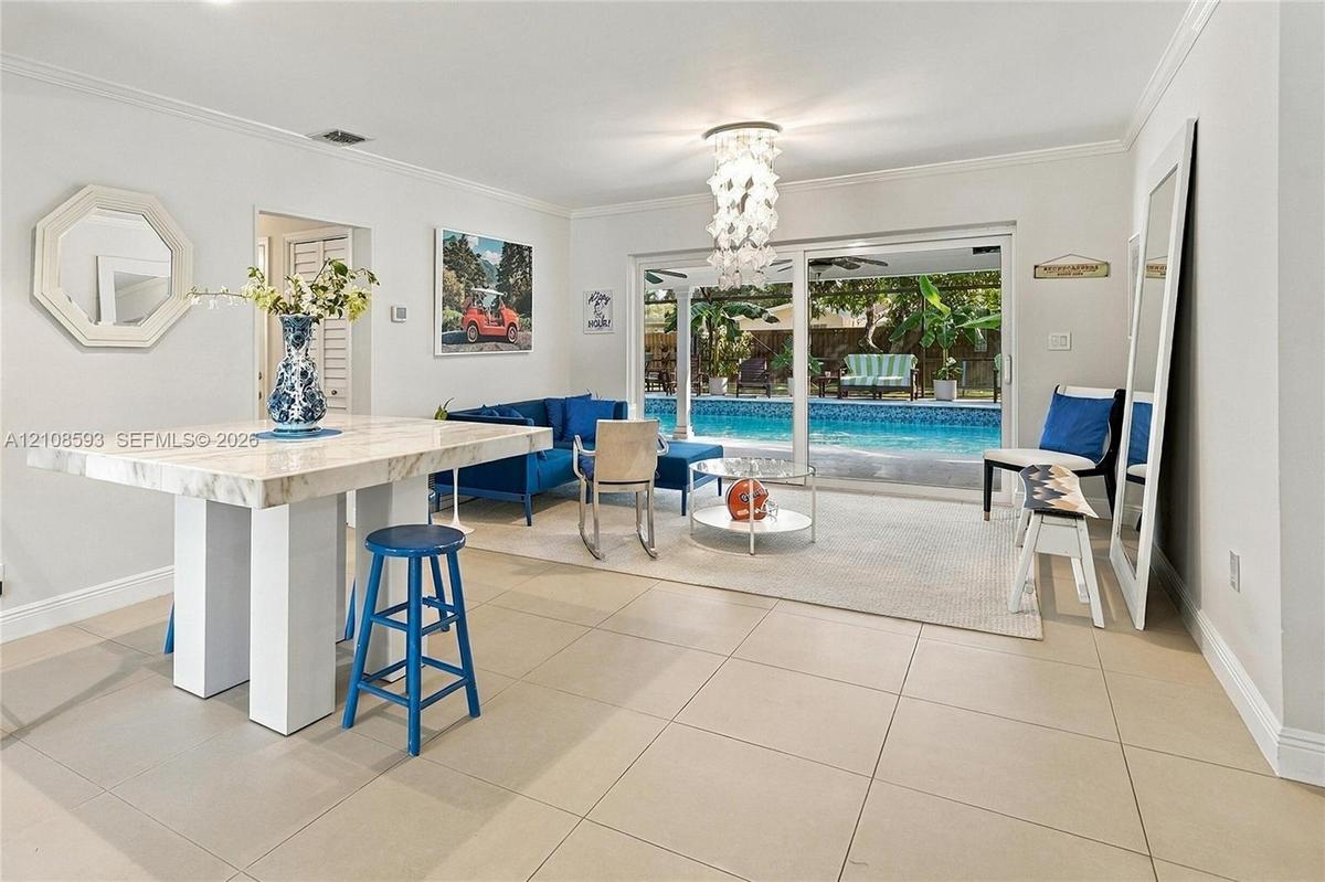 Large-format tile flooring, decorative multi-tiered light fixture, and sliding glass doors opening to an exterior swimming pool