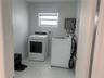 Laundry area featuring neutral-toned tile flooring, white walls, and a window with blinds