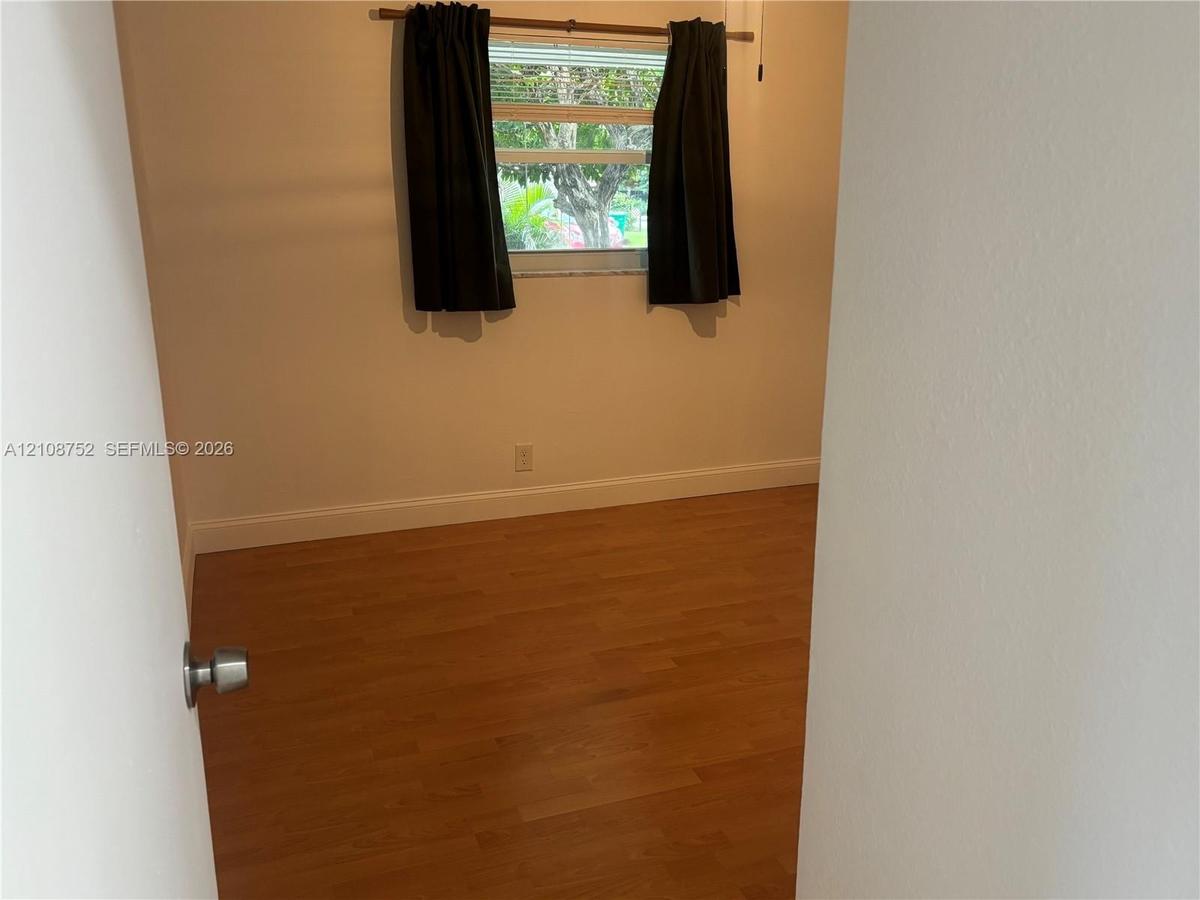 Room featuring wood-finish flooring, neutral-toned walls, and a horizontal sliding window