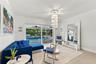 Interior space featuring crown molding, large-format tile flooring, a tiered crystal chandelier, and sliding glass doors revealing a screened-in pool