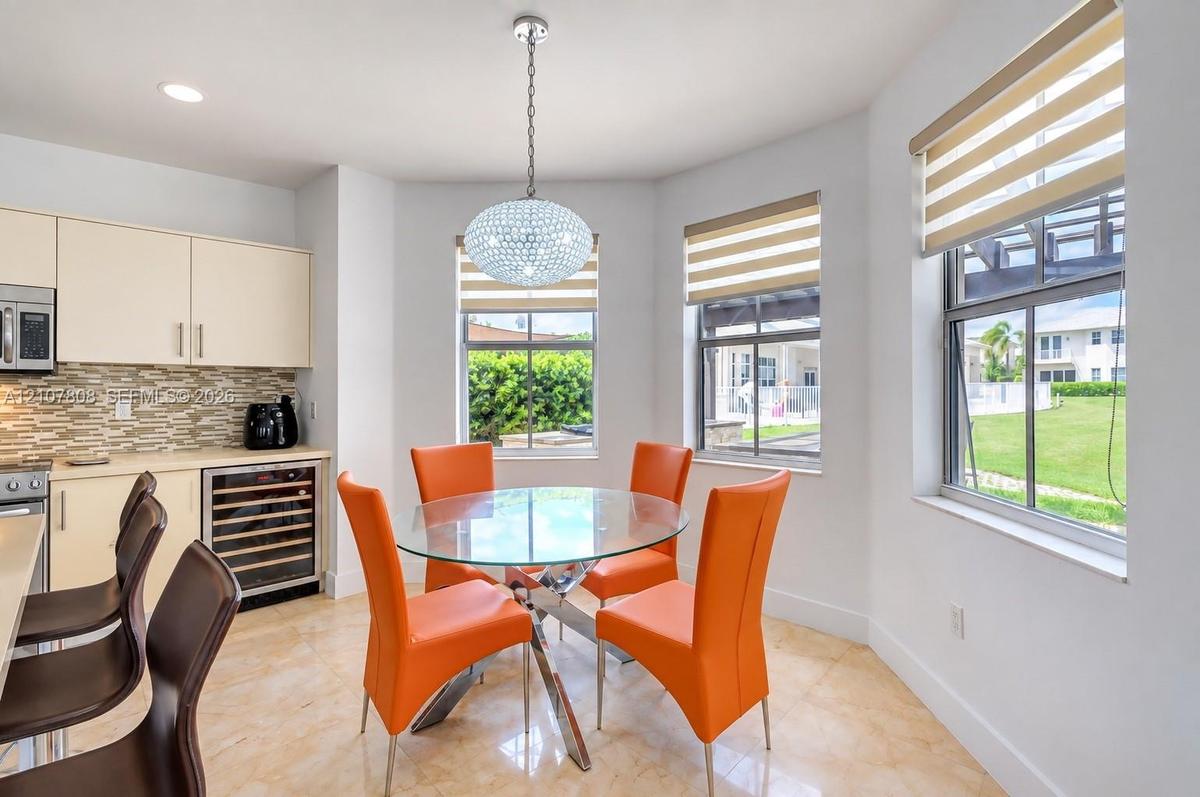 Kitchen area featuring flat-panel cabinetry, a built-in wine refrigerator, mosaic tile backsplash, recessed lighting, and a spherical crystal pendant 