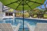 Screened-in patio area featuring a swimming pool with blue mosaic tile perimeter and concrete pool deck