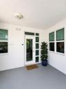 Covered porch entry featuring a glass-panel front door with vertical sidelights, textured exterior walls, smooth-finish flooring, and multiple dual-pa