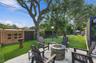 Backyard featuring a stone-paver patio, built-in circular stone fire pit, wood-lattice privacy screen, and mature trees
