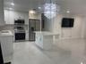 Kitchen featuring white shaker-style cabinetry, quartz countertops, stainless steel appliances, a central island, and large-format tile flooring