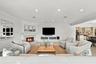 Living area featuring a painted brick corner fireplace with a mantel, recessed ceiling lighting, crown molding, and built-in cabinetry