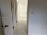 Interior hallway featuring large-format ceramic tile flooring, neutral wall finishes, and solid-core interior doors with satin nickel hardware