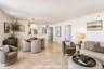 Open-concept interior featuring light stone flooring, crown molding, and a suspended globe pendant light fixture