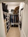 Walk-in closet featuring white built-in vertical shelving, integrated wire hanging rods, and tile flooring
