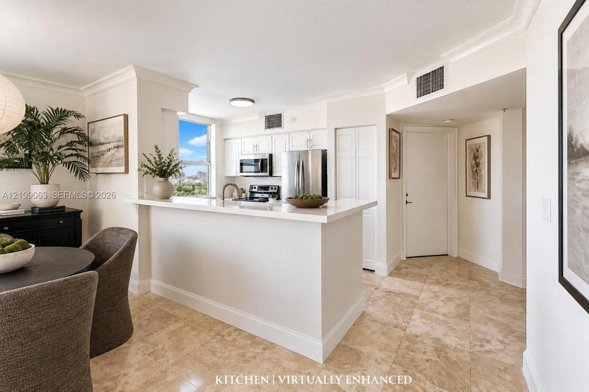 Kitchen featuring white cabinetry, solid-surface countertops with a breakfast bar, stainless steel appliances, and tile flooring
