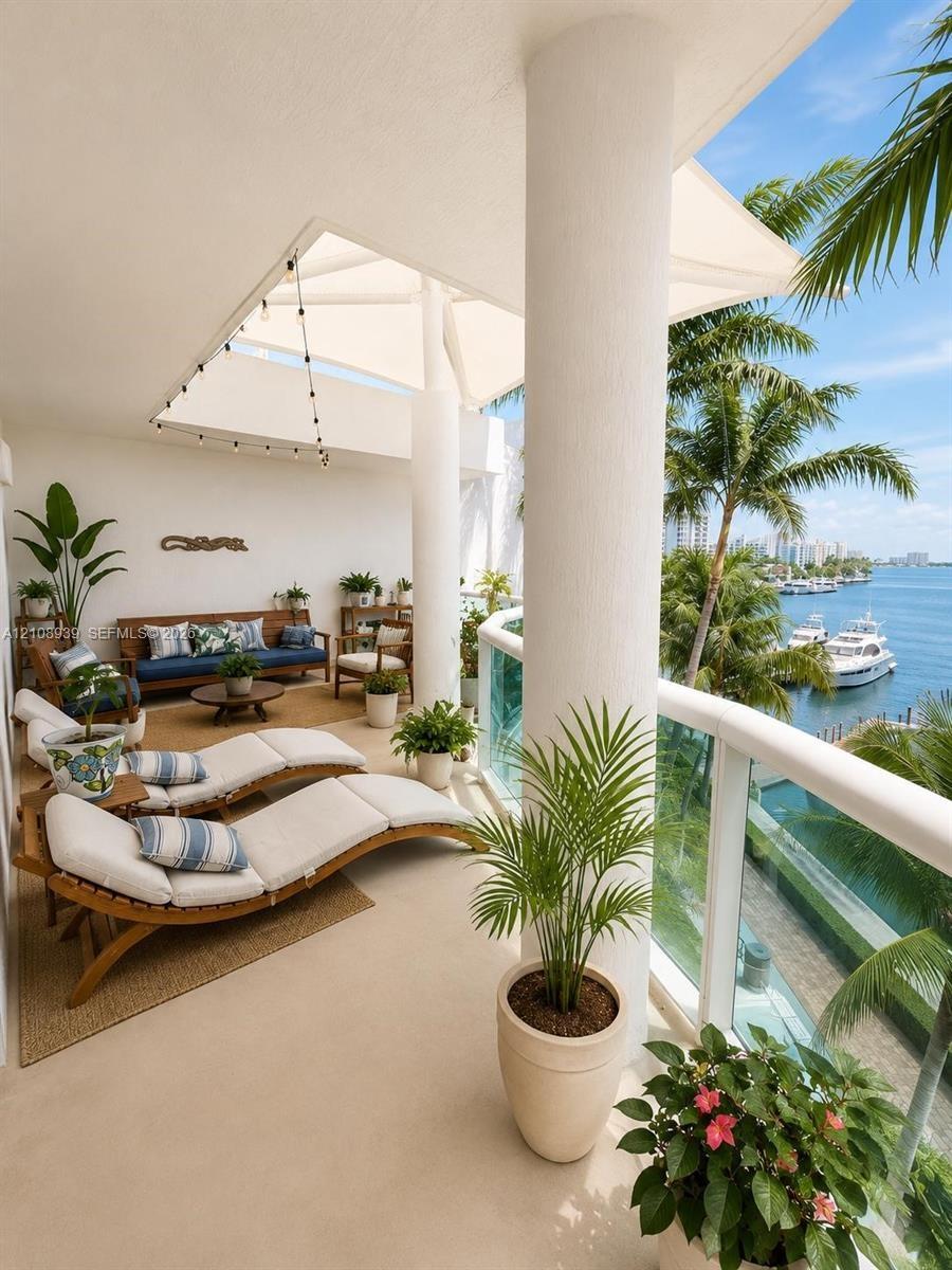 Covered terrace featuring structural columns, neutral-toned flooring, and a glass-paneled railing overlooking the waterfront
