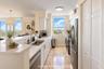 Kitchen featuring stone flooring, white cabinetry, quartz countertops, stainless steel appliances, and dual-basin stainless steel sink