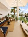 Covered terrace featuring a tensile fabric shade structure, glass panel railing, and concrete flooring, overlooking a water-facing landscape with matu