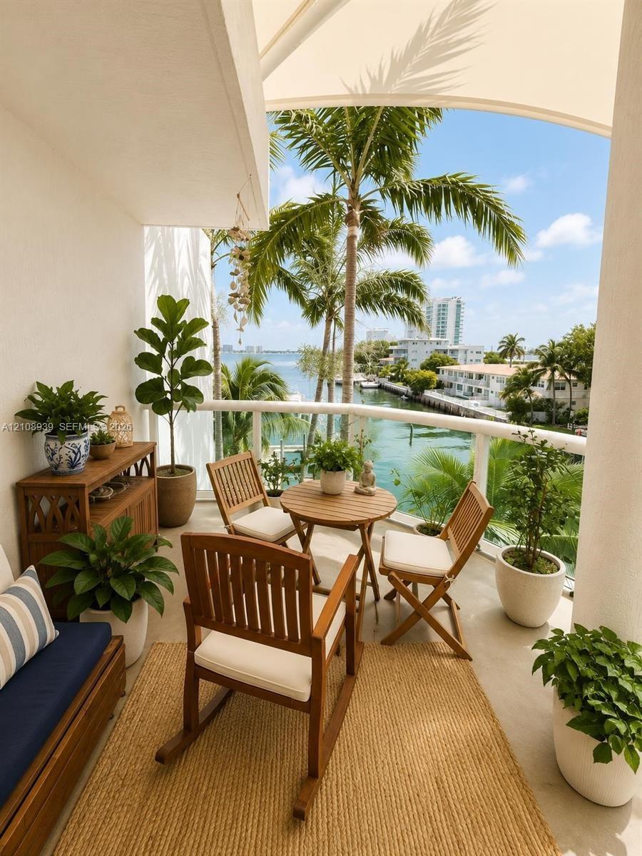 Covered balcony featuring a curved white structural railing and neutral stone-finish flooring