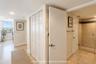 Neutral tile flooring, multi-panel bi-fold closet doors, and walk-in shower with stone-finish tile surround and recessed lighting