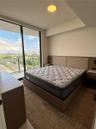 Floor-to-ceiling glass sliding doors, private balcony with metal railing, built-in wooden headboard with integrated lighting and electrical outlets, r