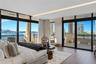 Floor-to-ceiling glass walls, integrated cove lighting, wood-finish flooring, and a wrap-around balcony with stone columns