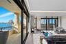 Floor-to-ceiling sliding glass walls, covered balcony with stone-finish pillar, wood-finish flooring, and recessed ceiling lighting