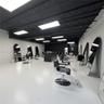 Open-concept interior featuring high-contrast black exposed ceiling trusses, bright rectangular LED panel lighting, polished light-reflective flooring