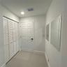 Six-panel interior door with matte black hardware, floor-to-ceiling louvered closet doors, and wall-mounted mirrors