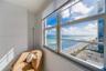 Large-pane windows with horizontal blinds featuring a direct perspective of the ocean and shoreline