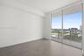 Large-format tile flooring, floor-to-ceiling windows, and balcony with metal railing