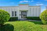 Stucco exterior featuring vertical structural fins, aluminum-framed glass entry door, and manicured landscaping
