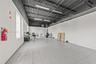 Expansive interior featuring high, exposed-joist ceilings, industrial-style black painted rafters, large rectangular ceramic tile flooring, and linear
