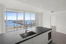 Kitchen island featuring a dark stone countertop, undermount stainless steel sink, pull-down chrome faucet, built-in wine refrigeration, and floor-to-