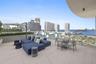 Expansive open-air terrace featuring large-format tile flooring, perimeter privacy planters, and glass balcony railings with metal accents