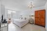 Bedroom featuring large windows, neutral tile flooring, and a decorative ceiling-mounted chandelier