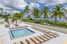 Swimming pool with tiled border, expansive paved patio, and perimeter metal fencing overlooking the oceanfront