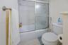 Bathroom featuring a combination bathtub and shower with a glass sliding enclosure, mosaic tile surround, and a wall-mounted towel bar