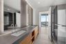 Dual-sink vanity with a solid-surface countertop, wood-finish cabinetry, floor-to-ceiling tile mirror surrounds, glass-enclosed shower, and large-form