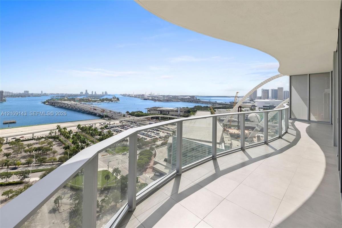 Curved balcony featuring large-format tile flooring and a glass panel railing