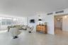 Open-concept interior featuring large-format ceramic tile flooring, expansive floor-to-ceiling windows, and neutral wall finishes